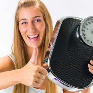 Diet and weight, young woman with a weight scale, she is happy about her success